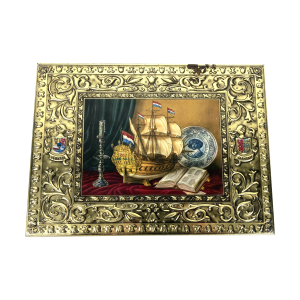 Verkade koekblik uit 1956. Titel: Golden Era. Afmeting: 31x23x5,5 cm. Blik, bestemd voor de export. Het goudkleurige blik heeft krullen in reliëf langs de rand van het deksel en de zijkanten. In het midden van het deksel een vlak met een stilleven van een schip, kandelaar, boek en Delfts blauw bord, met daarop een afbeelding van Frans Hals.