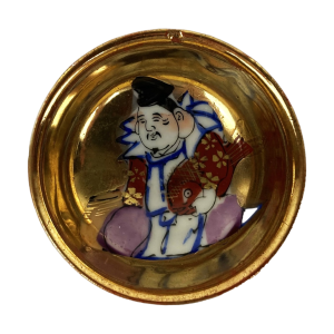Japans Kutani sake kommetje met één van de 7 Goden van voorspoed (de Shichifukujin). Handbeschilderd en gemerkt aan onderzijde. Diameter: 5 cm. Hoog: 2,5 cm. Een traditioneel verlovingsgeschenk in Japan.